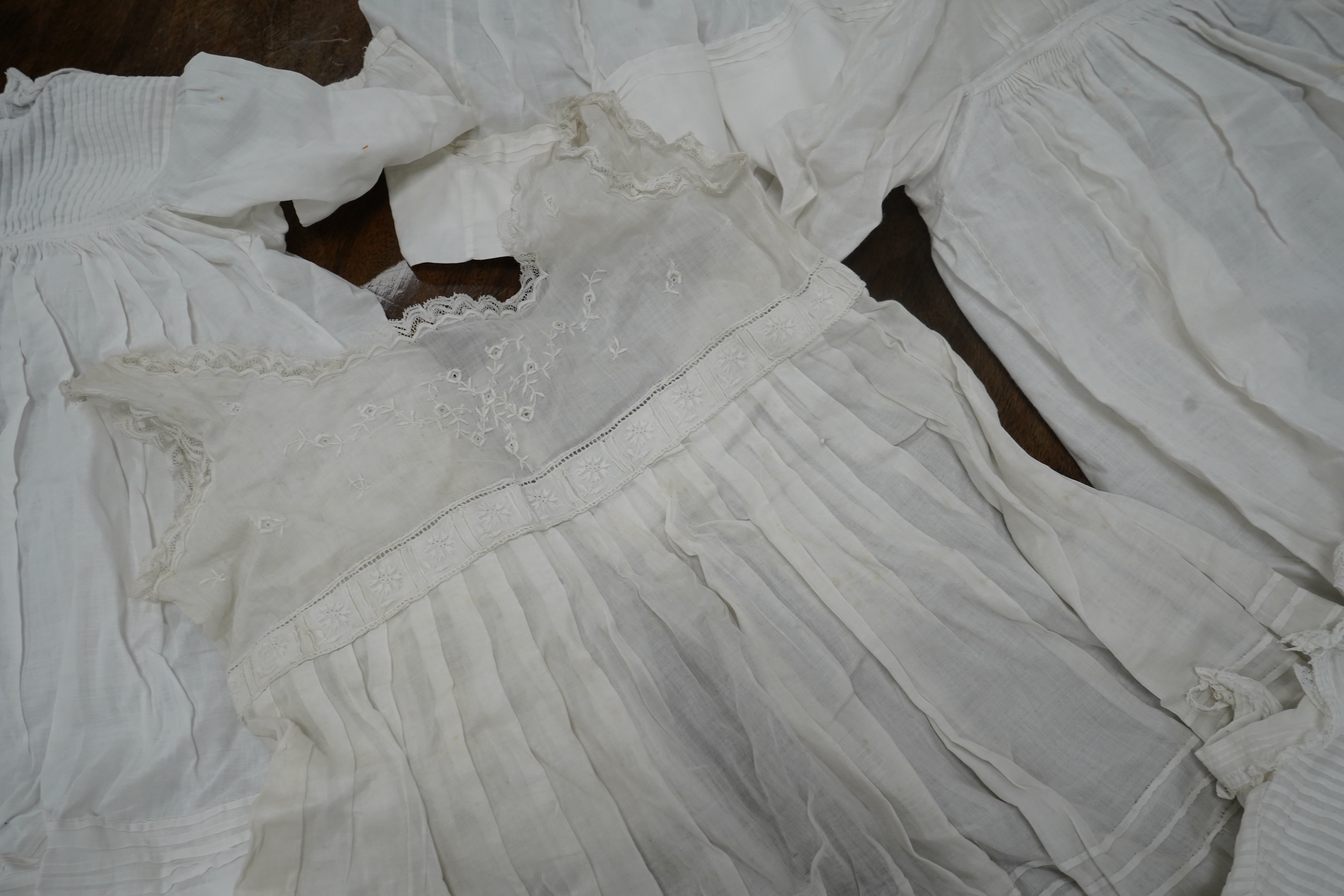 An early 20th century cream silk young girls day dress, together with six similar sized cotton and fine lawn day dresses and a bonnet, all dresses worked with tucking, feather stitching, some lace edged, the bonnet made